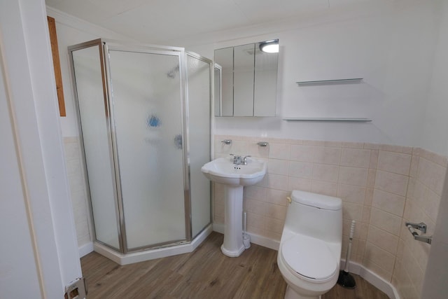 bathroom featuring wood-type flooring, toilet, tile walls, and a shower with shower door