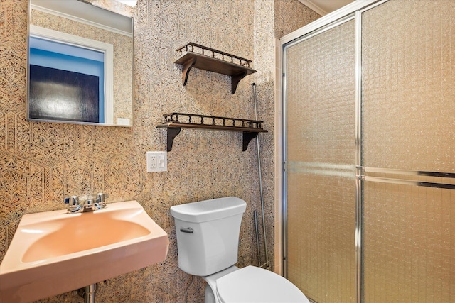 bathroom featuring crown molding, a shower with shower door, sink, and toilet