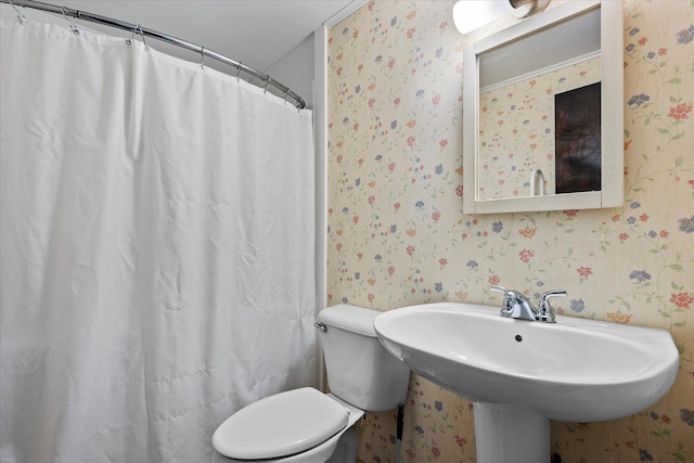 bathroom featuring a shower with shower curtain, toilet, and sink