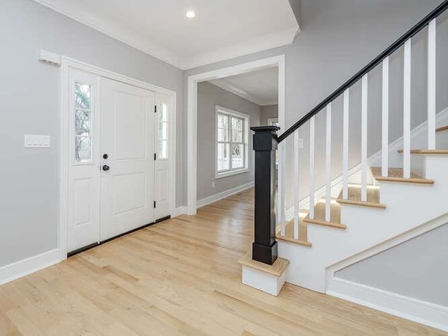 foyer entrance with ornamental molding and light hardwood / wood-style flooring