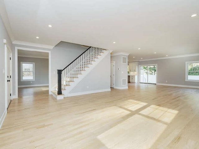 unfurnished living room featuring ornamental molding and light wood-type flooring