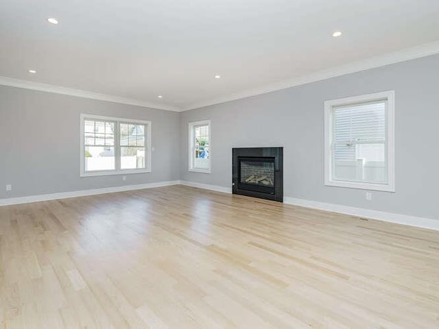 unfurnished living room with ornamental molding and light wood-type flooring