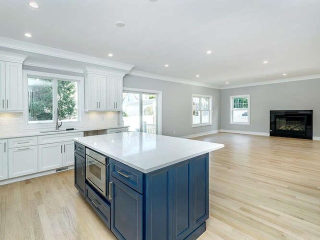 kitchen featuring sink, stainless steel microwave, white cabinets, and decorative backsplash