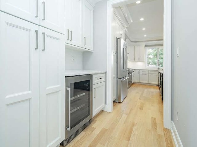 kitchen with wine cooler, white cabinetry, high end refrigerator, light wood-type flooring, and ornamental molding