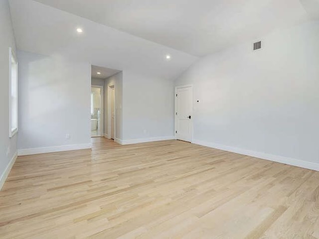 spare room featuring vaulted ceiling and light hardwood / wood-style floors