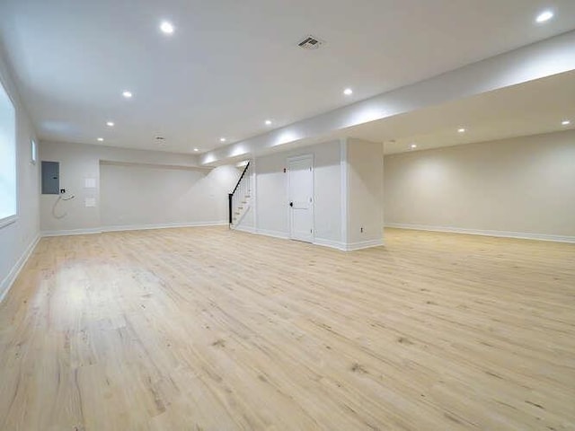 basement with electric panel and light wood-type flooring