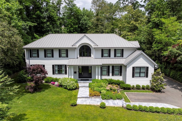 view of front of property with metal roof, a porch, aphalt driveway, a standing seam roof, and a front yard