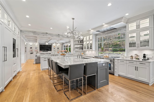 kitchen featuring a large island, glass insert cabinets, white cabinets, and a sink