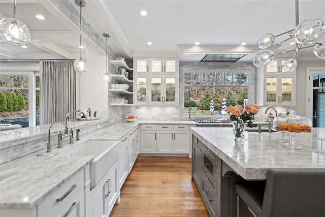 kitchen featuring open shelves, glass insert cabinets, white cabinets, and decorative light fixtures