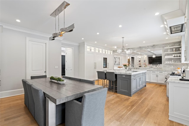 kitchen featuring decorative light fixtures, a spacious island, white cabinetry, a kitchen breakfast bar, and glass insert cabinets