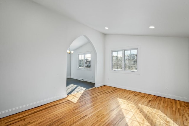 spare room featuring vaulted ceiling, light hardwood / wood-style flooring, and a notable chandelier