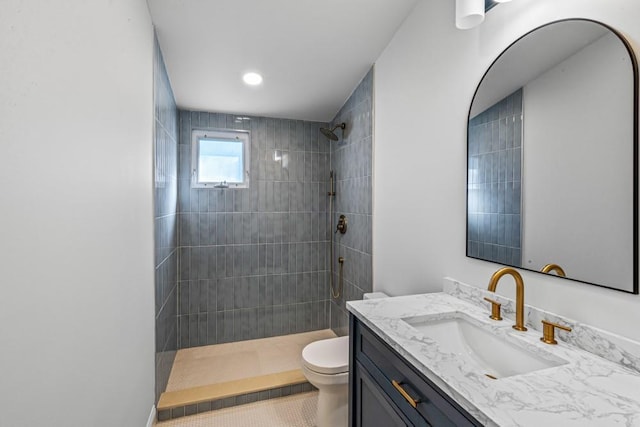 bathroom featuring vanity, toilet, and a tile shower