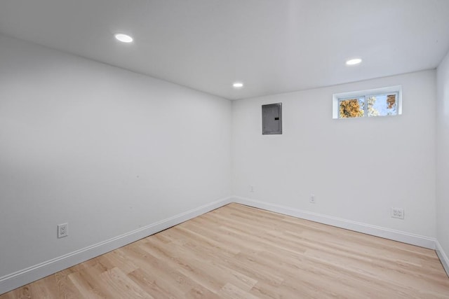 basement with electric panel and light hardwood / wood-style floors