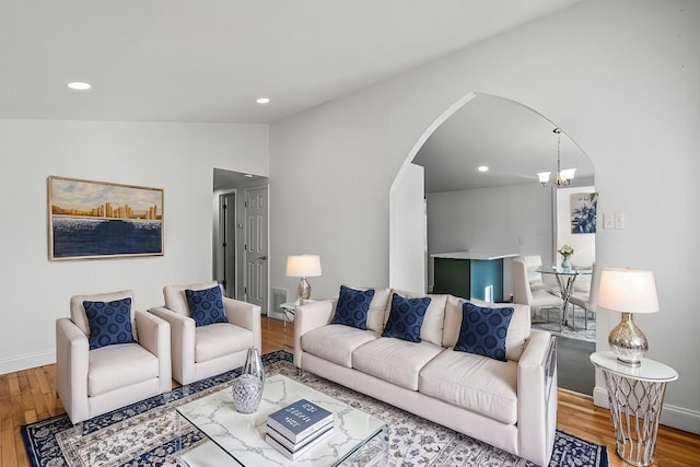 living room with a notable chandelier, wood-type flooring, and vaulted ceiling