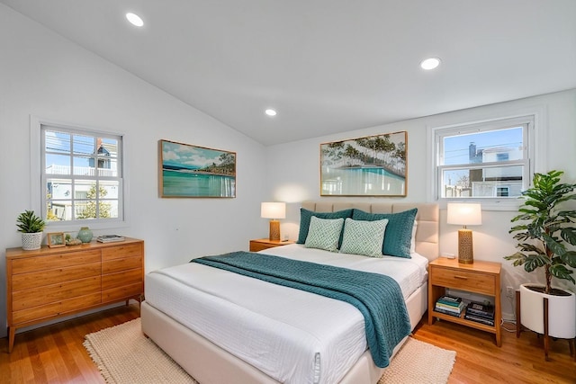 bedroom featuring multiple windows, lofted ceiling, and light hardwood / wood-style flooring