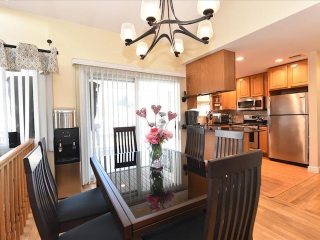 dining space with an inviting chandelier and light hardwood / wood-style flooring