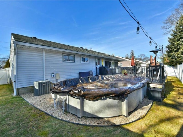 rear view of property featuring a pool side deck, a yard, and central AC unit