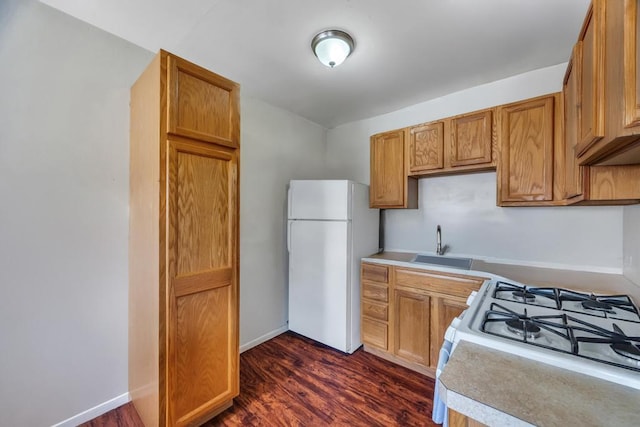 kitchen featuring brown cabinetry, white appliances, light countertops, and a sink