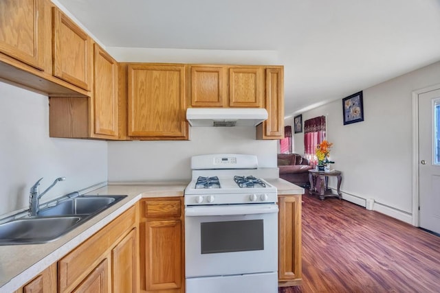 kitchen with under cabinet range hood, a sink, light countertops, white gas range oven, and dark wood finished floors