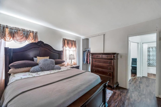 bedroom featuring dark wood-style floors, a walk in closet, and a closet