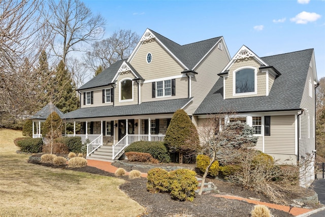 view of front of home with covered porch, a shingled roof, and a front yard