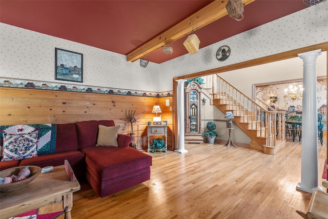 living room with wallpapered walls, stairway, wood finished floors, and ornate columns