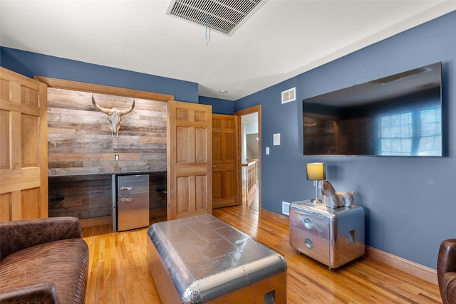 living area with baseboards, visible vents, and light wood-style floors