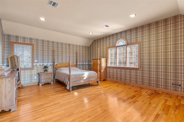 bedroom with wallpapered walls, baseboards, visible vents, and wood finished floors