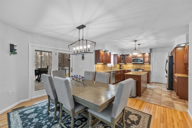 dining area featuring an inviting chandelier, sink, and light hardwood / wood-style flooring