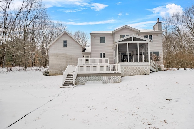 snow covered property with a wooden deck and a sunroom