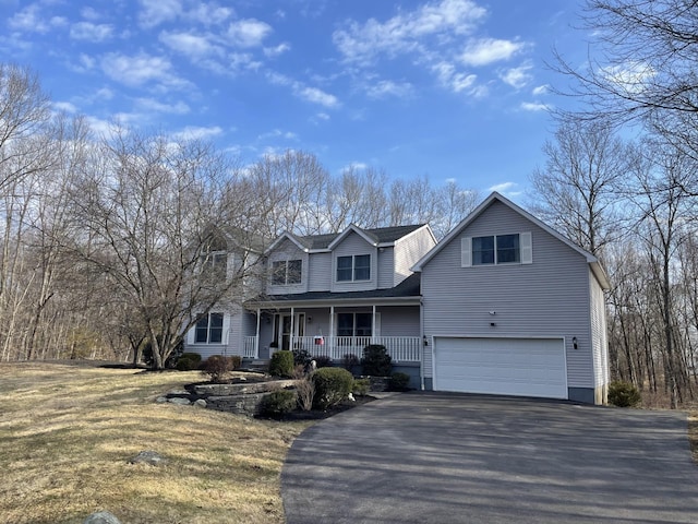 traditional-style house featuring covered porch, driveway, an attached garage, and roof with shingles