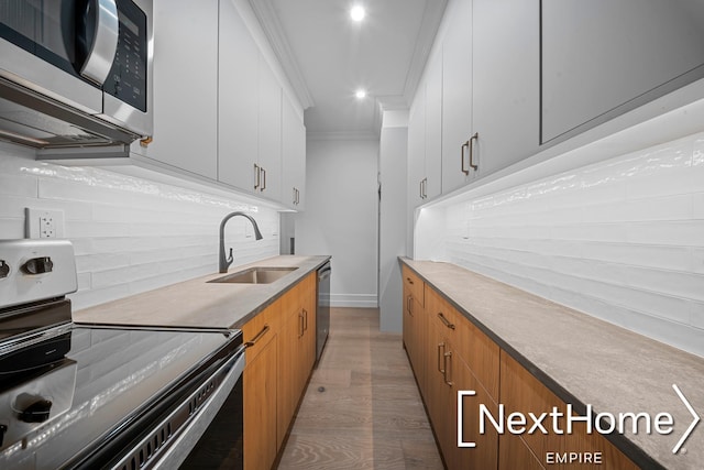 kitchen featuring tasteful backsplash, white cabinetry, sink, ornamental molding, and stainless steel appliances