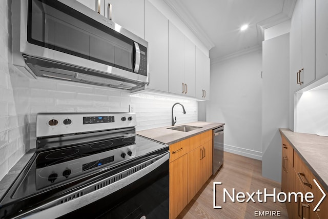 kitchen featuring white cabinetry, sink, backsplash, stainless steel appliances, and crown molding