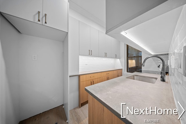 kitchen with white cabinetry, sink, decorative backsplash, and light hardwood / wood-style floors