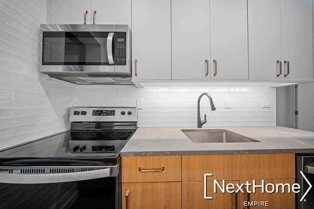 kitchen featuring tasteful backsplash, sink, white cabinets, and appliances with stainless steel finishes