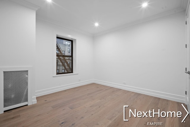 unfurnished room featuring ornamental molding, radiator, and light hardwood / wood-style floors