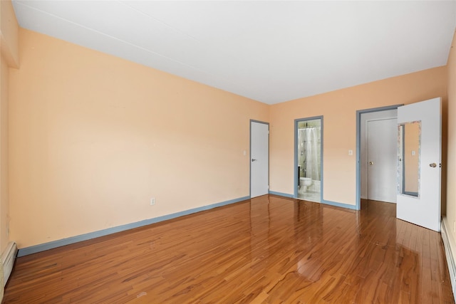 empty room with hardwood / wood-style flooring and a baseboard radiator