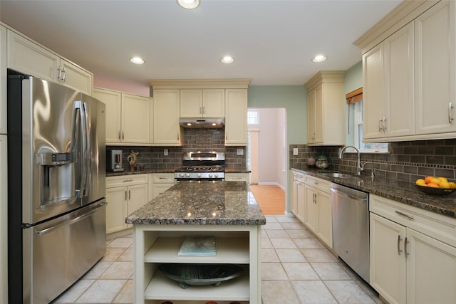 kitchen with stainless steel appliances, a sink, under cabinet range hood, and cream cabinets