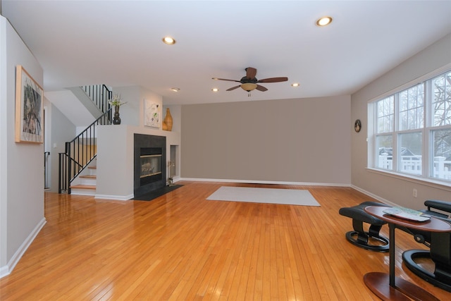 living area with recessed lighting, a fireplace, baseboards, stairs, and light wood finished floors