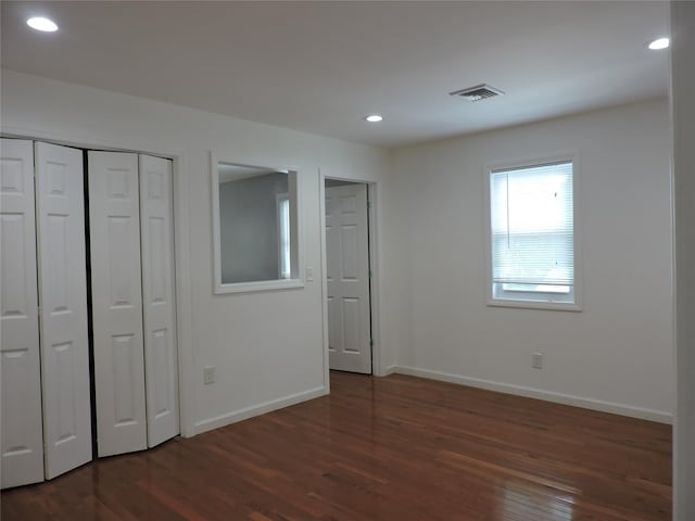 unfurnished bedroom featuring dark hardwood / wood-style flooring and a closet