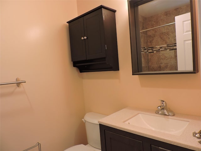 bathroom featuring vanity, tiled shower, and toilet