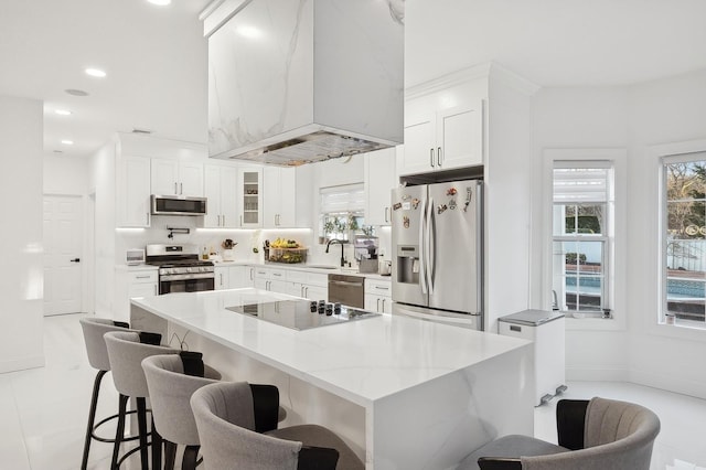 kitchen featuring a breakfast bar, stainless steel appliances, a center island, ventilation hood, and white cabinets