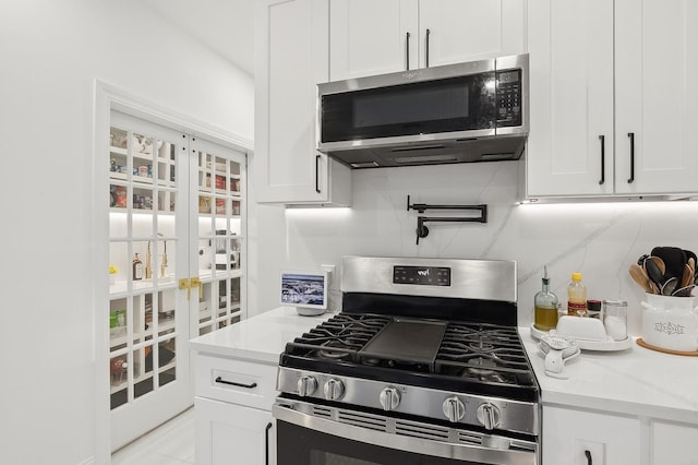 kitchen featuring light stone counters, appliances with stainless steel finishes, backsplash, and white cabinets