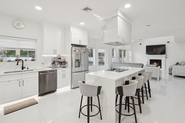 kitchen with a kitchen bar, sink, a center island, stainless steel appliances, and white cabinets