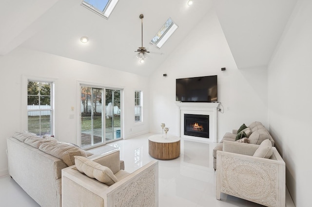 living room featuring ceiling fan, high vaulted ceiling, and a skylight