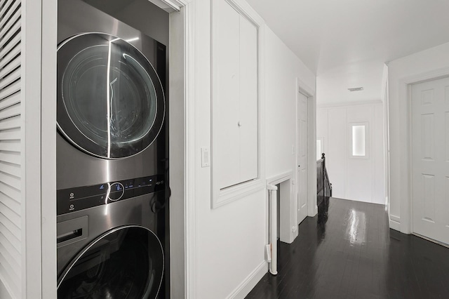 clothes washing area featuring stacked washing maching and dryer and dark hardwood / wood-style flooring