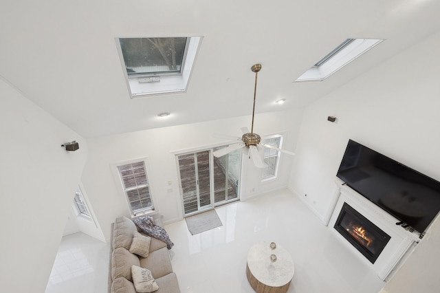 living room with vaulted ceiling with skylight and ceiling fan