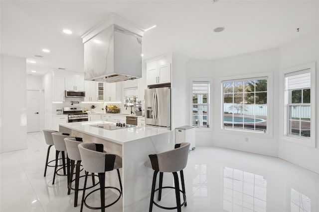 kitchen with light tile patterned floors, appliances with stainless steel finishes, white cabinetry, a kitchen breakfast bar, and a kitchen island