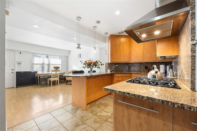 kitchen with black gas cooktop, tasteful backsplash, decorative light fixtures, kitchen peninsula, and wall chimney range hood