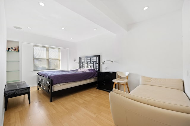 bedroom with beamed ceiling and light hardwood / wood-style flooring